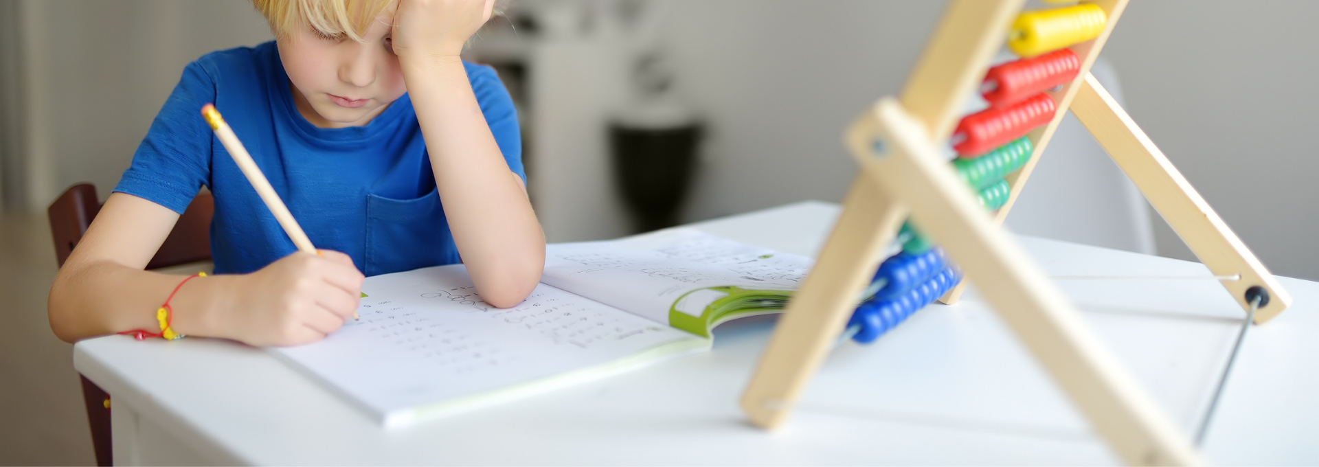 Enfant assis à un bureau, concentré sur un exercice écrit, montrant des signes de difficulté d’attention lors d’une activité scolaire.