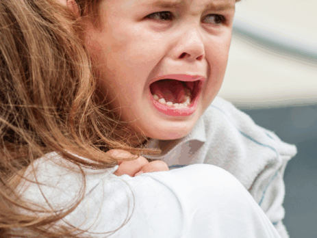 Jeune enfant en pleurs, réconforté par un adulte, illustrant les émotions et l’anxiété que certains enfants peuvent vivre à l’approche de la rentrée scolaire.