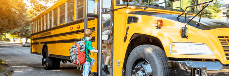 Enfant portant un sac à dos montant dans un autobus scolaire jaune par une matinée ensoleillée.
