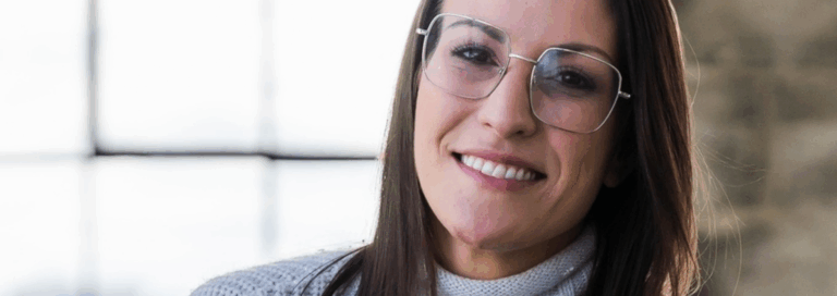 Portrait de Caroline Quarré, intervenante psychosociale, souriante, portant des lunettes, dans un environnement lumineux.