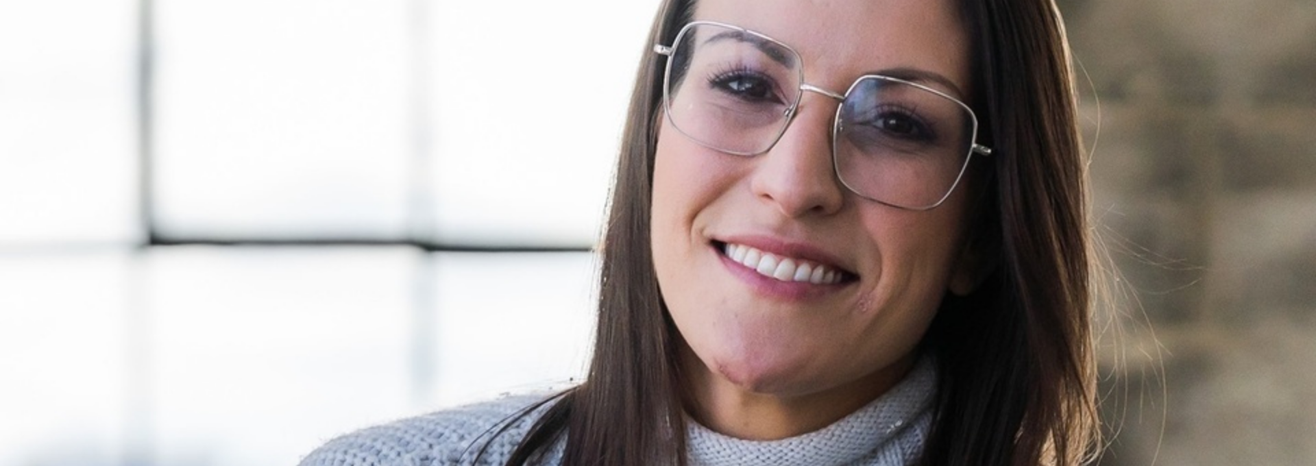 Portrait de Caroline Quarré, intervenante psychosociale, souriante, portant des lunettes, dans un environnement lumineux.