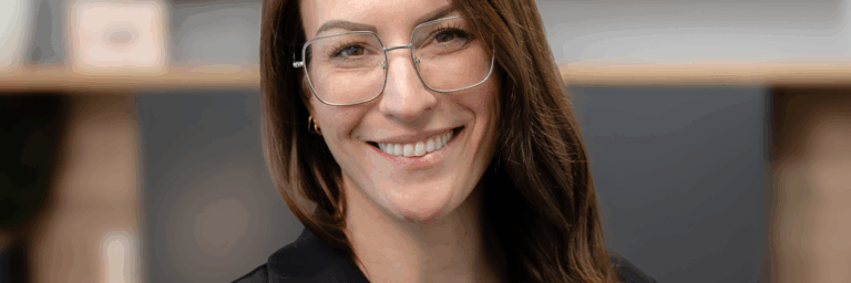 Portrait de Caroline Quarré, intervenante psychosociale et autrice, souriante, portant des lunettes, dans un environnement professionnel.