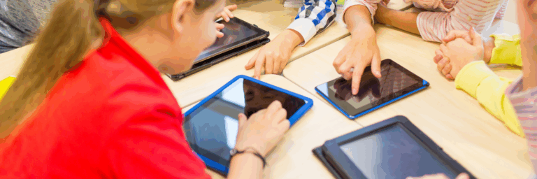 Enfants réunis autour d’une table utilisant des tablettes numériques, illustrant l’exposition aux écrans et les usages numériques chez les jeunes.