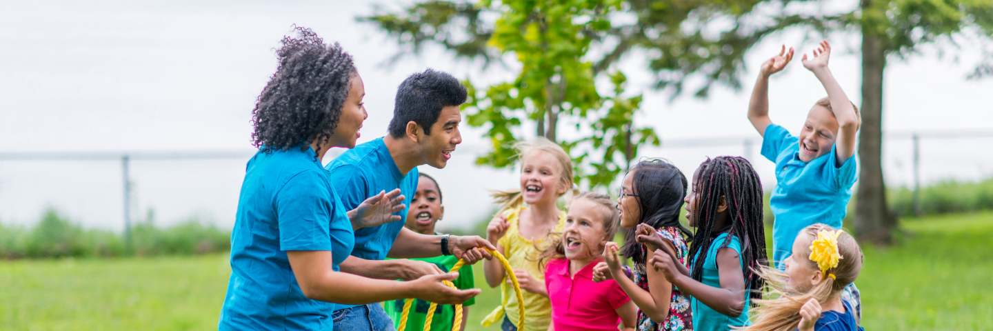 Des enfants participent à une activité de groupe en plein air, accompagnés de deux animateurs, dans le cadre d’un programme favorisant les habiletés sociales et le bien-être psychologique.