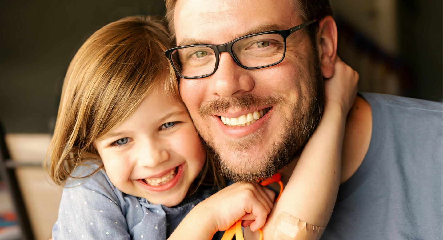 Père et enfant souriants, enlacés à la maison.